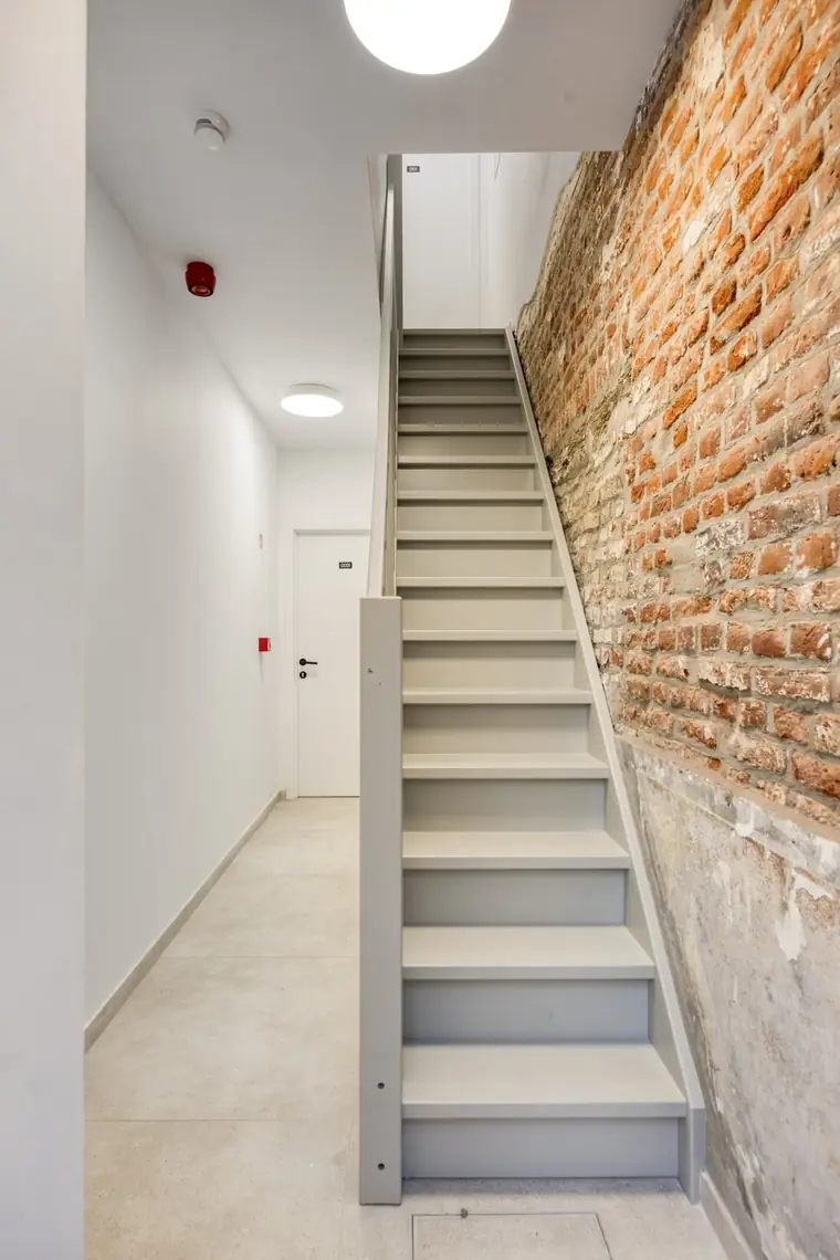 Gemeenschappelijke inkomhal en trap met bewaarde bakstenen muur